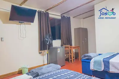 a room with two beds and a flat screen tv at SONCCO LODGE-RESTAURANT in Quillabamba
