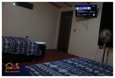 a room with two beds and a fan and a television at SONCCO LODGE-RESTAURANT in Quillabamba