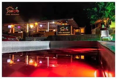 a restaurant with a reflection in the water at night at SONCCO LODGE-RESTAURANT in Quillabamba