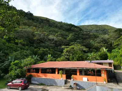 a house with a red car parked in front of a mountain at SONCCO LODGE-RESTAURANT in Quillabamba