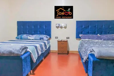 two beds in a room with blue tufted beds at SONCCO LODGE-RESTAURANT in Quillabamba