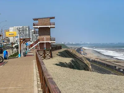 a building on a beach next to the ocean at Exclusivo con vista panorámica al mar - Ocean View in Lima