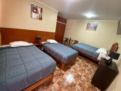 a hotel room with two beds and a table at LA FAMILIA NASCA HOUSE in Nazca