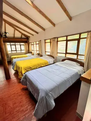 three beds in a room with windows at Andenes del Sol in Cusco
