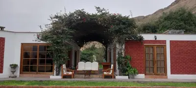 a group of white chairs sitting under an arch at Las buganvilias in Pachacamac
