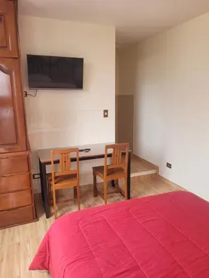 a bedroom with a bed and a desk with two chairs at Habitación con baño propio para 2 personas como máximo in Lima