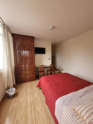 a bedroom with a bed with a red blanket and a table at Habitación con baño propio para 2 personas como máximo in Lima