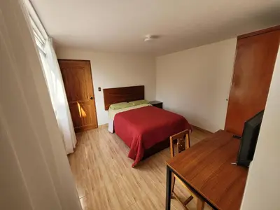 a small bedroom with a bed with a red blanket at Habitación con baño propio para 2 personas como máximo in Lima