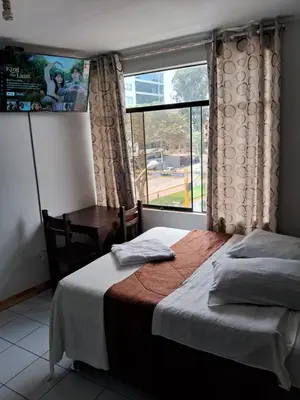 a bedroom with a bed and a desk and a window at LAS ARTES INN in Lima