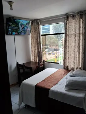 a bedroom with a bed and a desk and a window at LAS ARTES INN in Lima