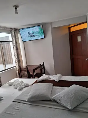 a bedroom with two beds and a tv on the wall at LAS ARTES INN in Lima