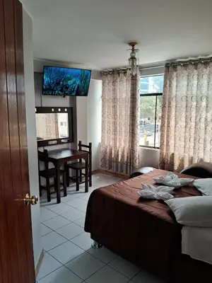 a bedroom with a bed and a table and a window at LAS ARTES INN in Lima
