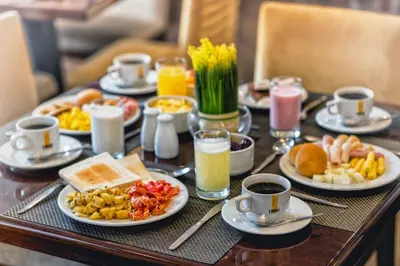 a breakfast table with plates of food and cups of coffee at LimaQ Hotel in Lima
