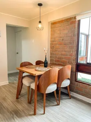 a dining room table with chairs and a brick wall at Miraflores House C&F in Lima