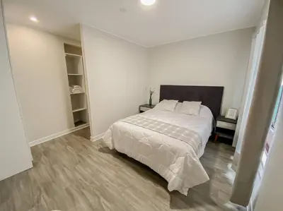 a white bedroom with a large bed and wooden floors at Miraflores House C&F in Lima