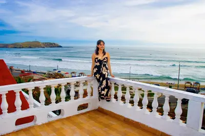 a woman standing on a balcony overlooking the ocean at HOTEL CHORRILLOS BEACH in Barranca