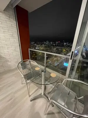 a glass table and chairs on a balcony with a view at Beautiful loft at heart of Lima in Lima