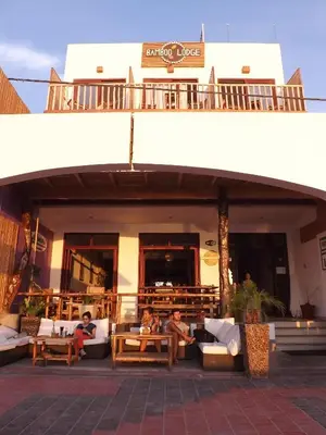 a group of people sitting on benches outside of a building at Bamboo Lodge Paracas in Paracas