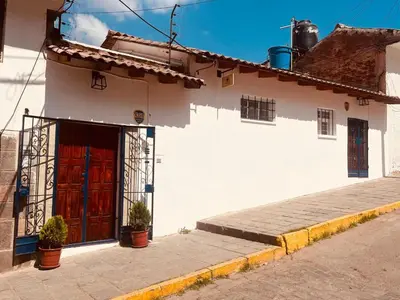 a white building with a red door on a street at Saqray Hostel in Cusco
