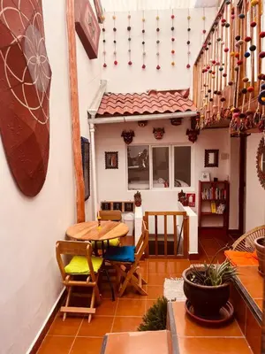 a patio with a table and chairs and a house at Saqray Hostel in Cusco