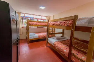 a room with three bunk beds and a window at Casa Machu Picchu Hostel in Machu Picchu