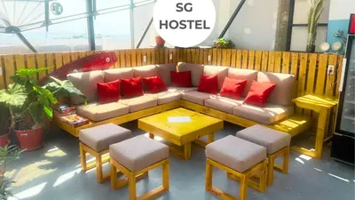 a couch with red pillows and a table and chairs at SG Paracas Hostel in Paracas