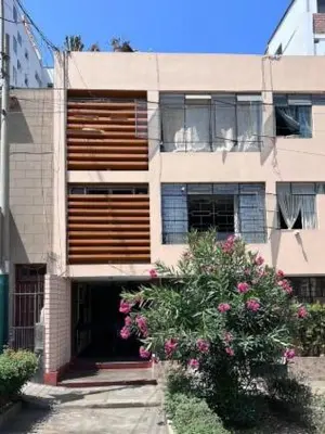 a building with pink flowers in front of it at Siempre Listo in Lima