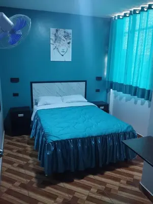 a blue bedroom with a bed with a blue wall at Hostal El Pilar in Lima