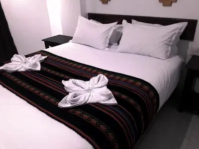 a bed with white blankets and bows on it at PAKARINA HOTEL in Machu Picchu