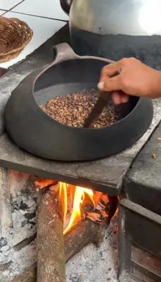 a person cooking food in a pan over a fire at Refugio de Mery Lucmabamba in Sahuayacu