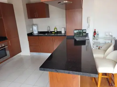 a kitchen with a black counter top and wooden cabinets at Moderno departamento cerca al malecón in Lima