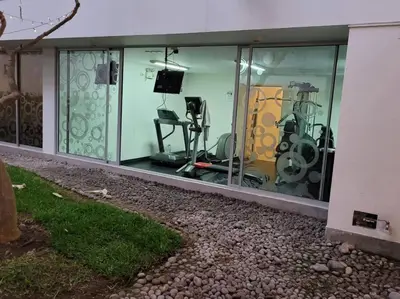 a house with glass windows with exercise equipment inside at Moderno departamento cerca al malecón in Lima
