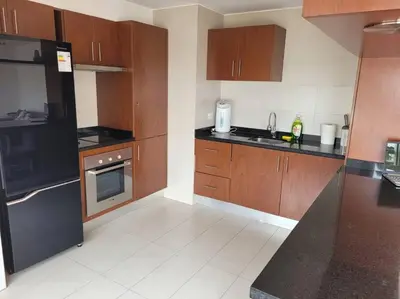 a kitchen with wooden cabinets and a black refrigerator at Moderno departamento cerca al malecón in Lima