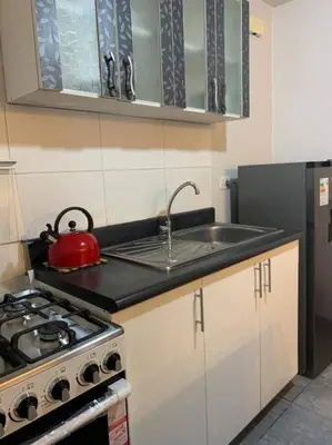 a kitchen with a stove and a red tea kettle at 807. Departamento entero en Chorrillos in Lima