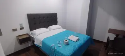 a bedroom with a large bed with a blue comforter at Hotel Grand Paradise Marcona in San Juan de Marcona
