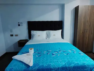 a bedroom with a bed with a blue comforter with fishes on it at Hotel Grand Paradise Marcona in San Juan de Marcona