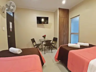 a hotel room with two beds and a table at Hotel Sand and Lake in Ica