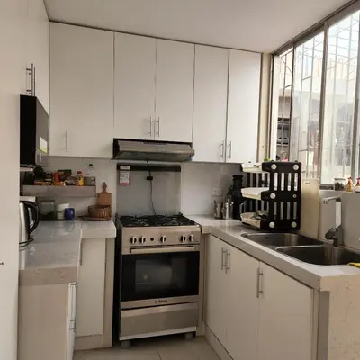 a kitchen with white cabinets and a stove and a sink at Casa Cultura II in Lima