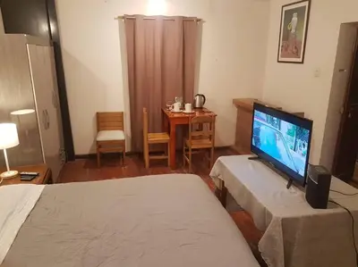 a room with a bed and a television and a table at Nico Homes in Cusco