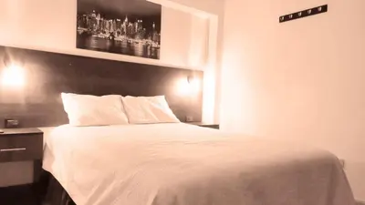 a bedroom with a white bed with a black headboard at ANDAHUAYLAS CENTRO in Andahuaylas
