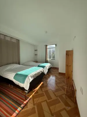 two beds in a room with wooden floors at Vertigo Climbing Hostel in Urubamba