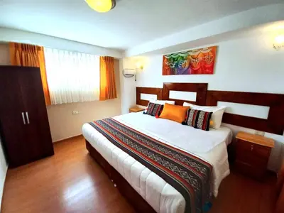 a bedroom with a large bed with orange pillows at Hotel Humantay lodge Ollantaytambo in Ollantaytambo