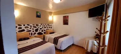 a hotel room with two beds and a tv at Hotel Humantay lodge Ollantaytambo in Ollantaytambo