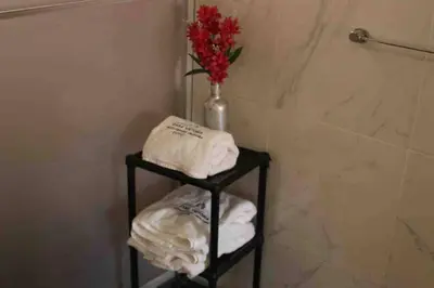 a bathroom with a shelf with towels and a vase of flowers at Casa Machupicchu - Huayllabamba, Urubamba Cusco, Perú in Huayllabamba