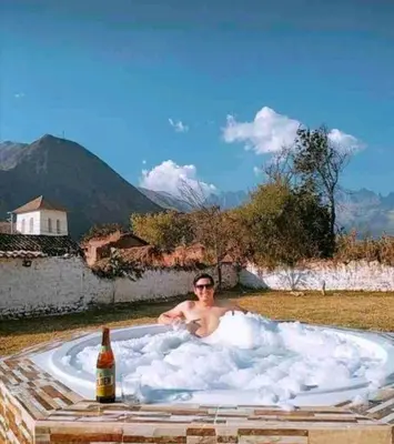 a man in a bath tub with a bottle of beer at Casa Machupicchu - Huayllabamba, Urubamba Cusco, Perú in Huayllabamba