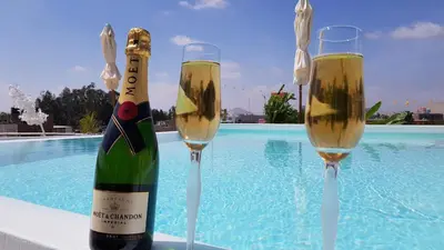 two glasses of champagne sitting next to a swimming pool at Ollanta Rooftop Adults only in Ica