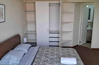 a bedroom with a bed and open shelving at apartamento de estreno con balcón frente al mar. in Lima