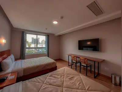 a hotel room with two beds and a desk and a tv at MIRAFLORES CITY HOTEL in Lima