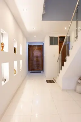 a hallway of a house with white floors and a wooden door at Casa completa, 5 dormitorios y jardín in Ayacucho