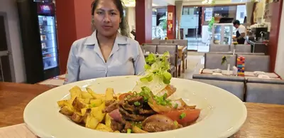 a woman sitting at a table with a plate of food at TAYWA HOTEL in Machu Picchu